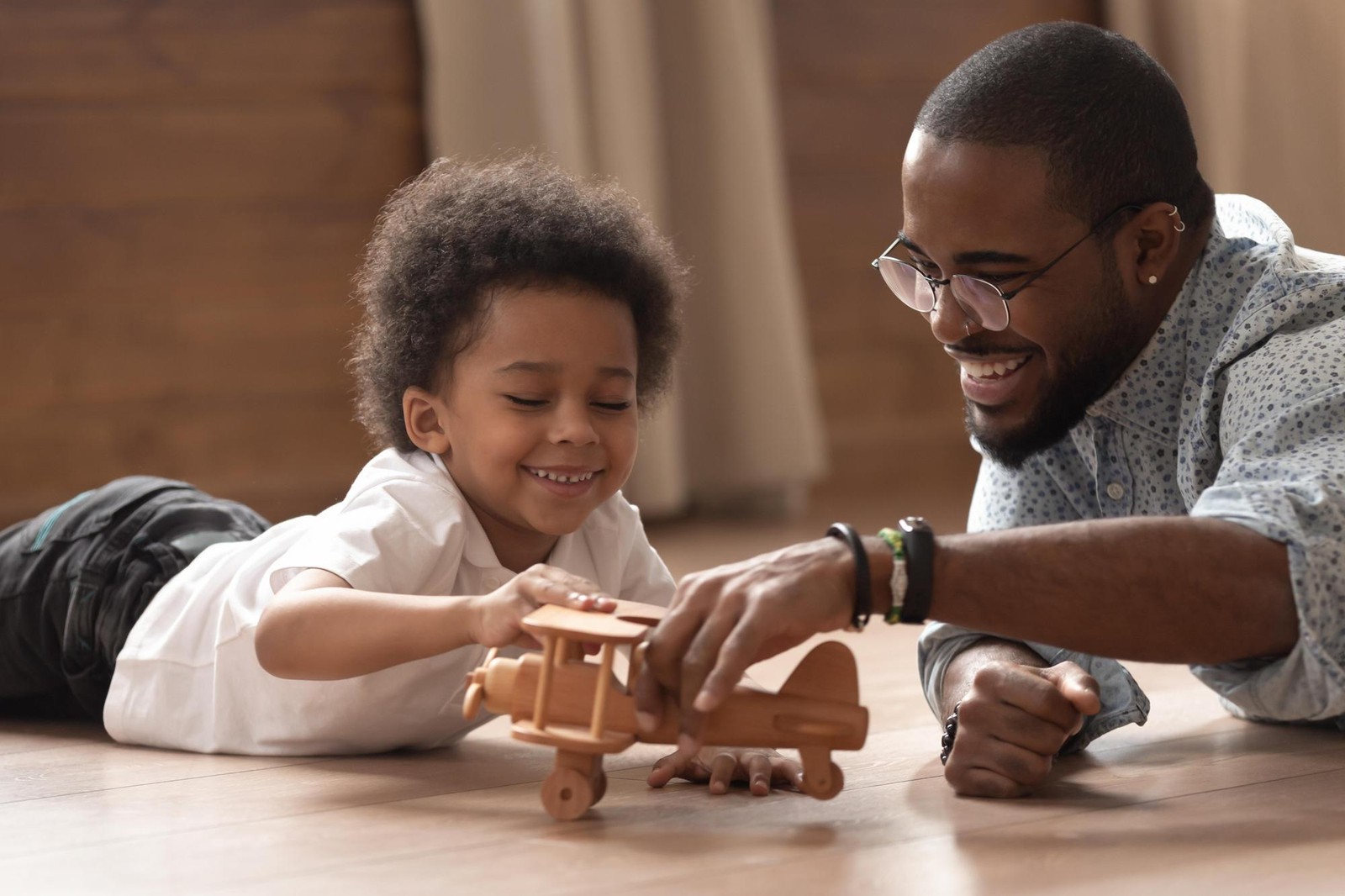 African-American father playing with his son and a toy airplane