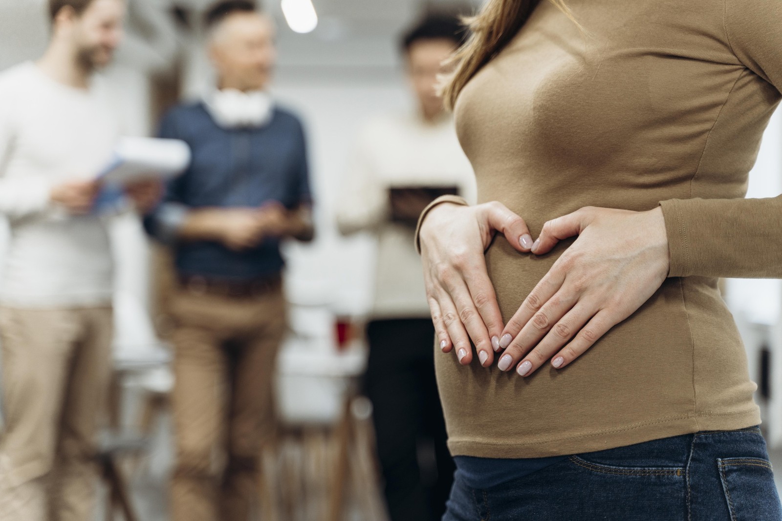 Pregnant businesswoman making a heart shape over her belly